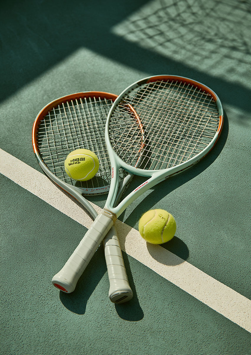 Artistic depiction of tennis rackets and balls arranged on a green court.