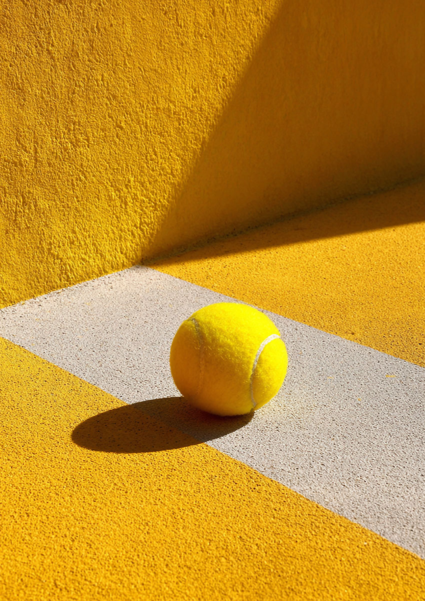 Dramatic artwork of a tennis ball on a vibrant yellow court surface